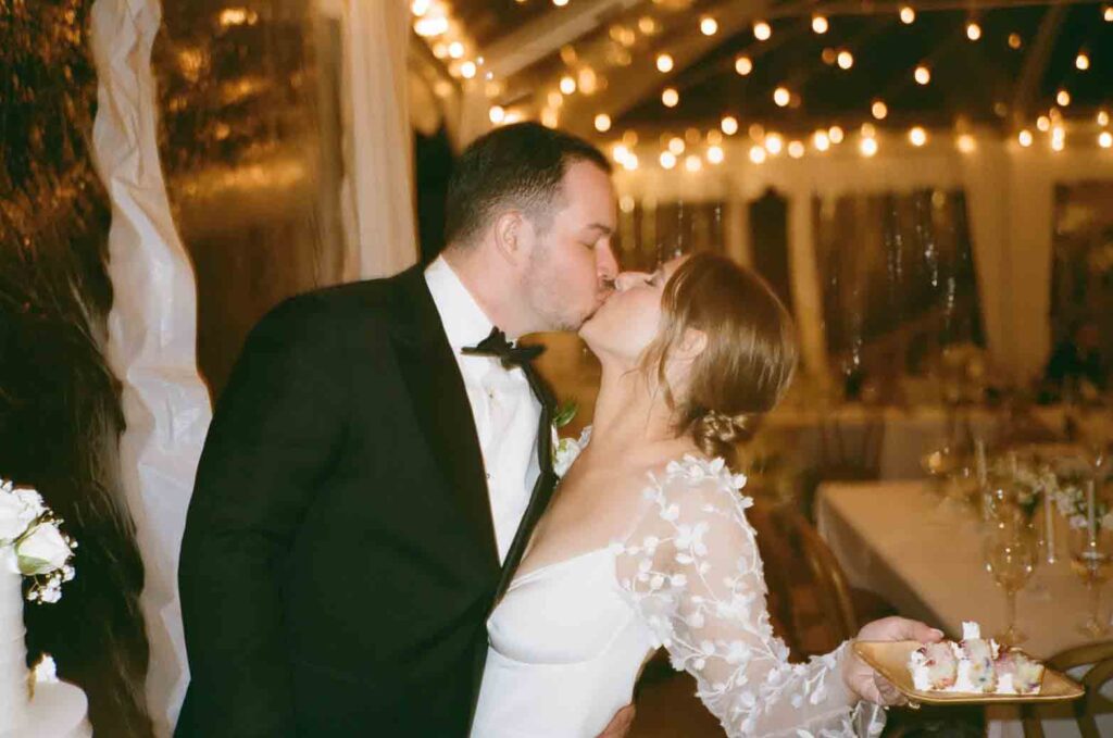 Kim and Stu eating their wedding cake and kissing at their Washington DC wedding venue