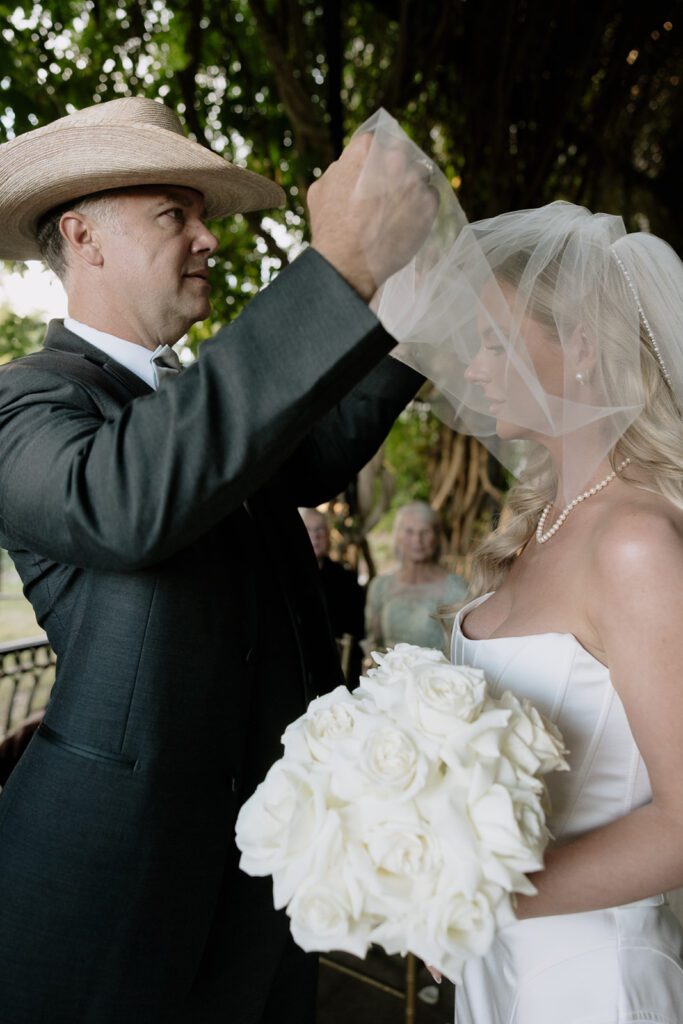 The father of the bride taking the brides blusher off on her wedding day.