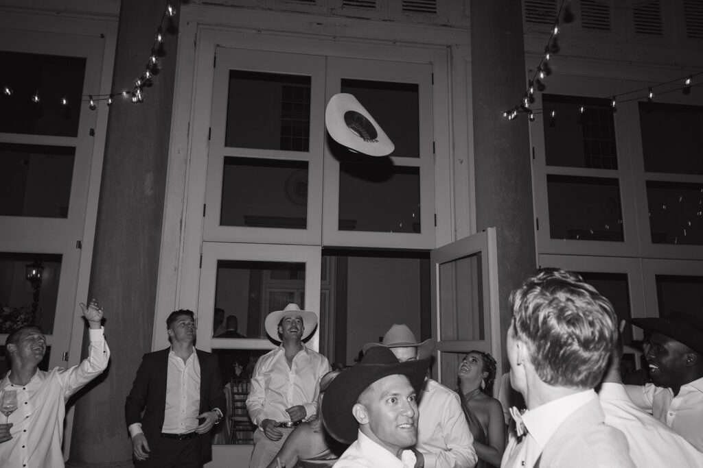 A cowboy hat flies up in the air on a wedding night.
