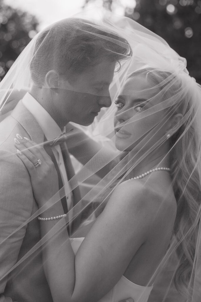 Bride and groom posing for their wedding portraits under her veil.