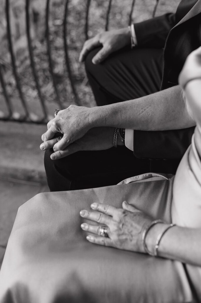 Parents of the groom holding hands during his wedding ceremony.