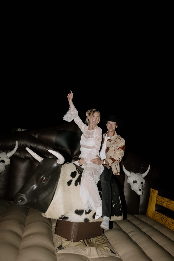 A bride and groom riding a mechanical bull at their welcome party in Nashville, Tennessee.